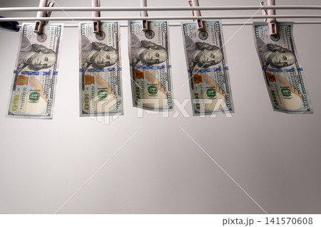 Row of one hundred dollar bills hanging on white drying rack Row of one hundred dollar bills hanging on white drying rack 141570608