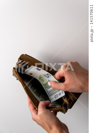 Woman hands taking five euro banknote out of leather wallet Woman hands taking five euro banknote out of leather wallet 141570611