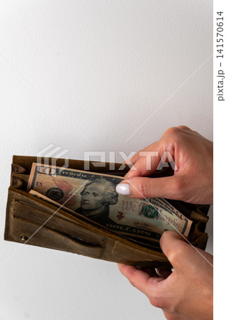 Woman hands holding brown leather wallet with ten dollar banknote Woman hands holding brown leather wallet with ten dollar banknote 141570614