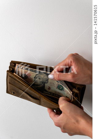 Woman hands holding brown leather wallet with ten dollar banknote Woman hands holding brown leather wallet with ten dollar banknote 141570615