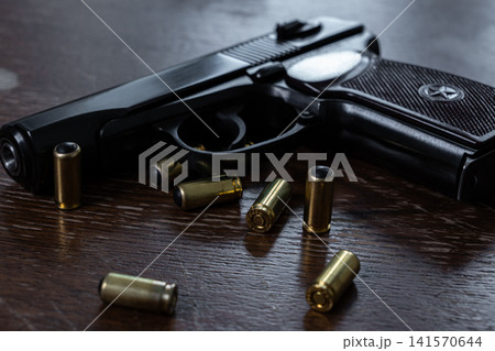 Black semi automatic pistol with rubber bullet cartridges on wooden table Black semi automatic pistol with rubber bullet cartridges on wooden table 141570644