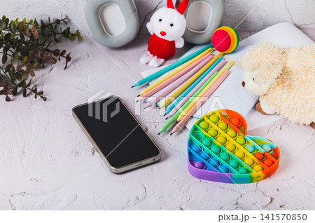 Social media ban concept for children. Smartphone and toys on the table. Social media ban concept for children. Smartphone and toys on the table. 141570850