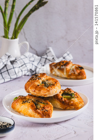 Delicious puff pastry buns with cheese and asparagus on a plate on the table vertical view Delicious puff pastry buns with cheese and asparagus on a plate on the table vertical view 141570861