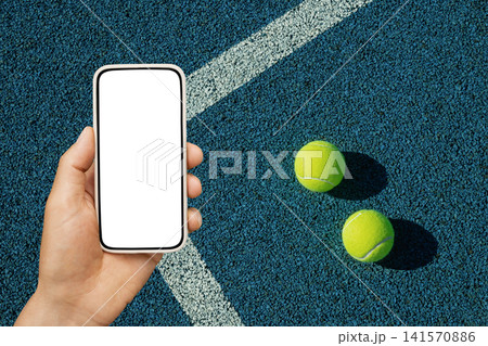 Smartphone mockup in hand on tennis court with balls Smartphone mockup in hand on tennis court with balls 141570886