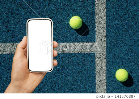Smartphone mockup in hand on tennis court with balls 141570887
