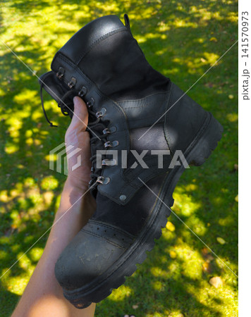 Hand Holding Black Work Boot in Outdoor Setting Hand Holding Black Work Boot in Outdoor Setting 141570973