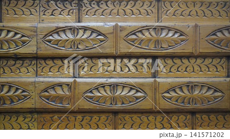 Detailed architectural pattern of carved wooden panels in a warm honey-gold color, craftsmanship concept. Detailed architectural pattern of carved wooden panels in a warm honey-gold color, craftsmanship concept. 141571202