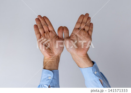 Human hands in a light blue dress shirt creating an open gesture against a simple background, symbolizing concepts of invitation, freedom, or protection Human hands in a light blue dress shirt creating an open gesture against a simple background, symbolizing concepts of invitation, freedom, or protection 141571333