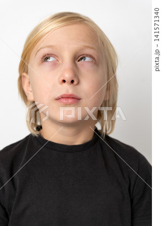 Young blonde boy looking up and to the side with a pensive expression, representing concepts of thinking, imagination, curiosity, and concentration on a plain white background Young blonde boy looking up and to the side with a pensive expression, representing concepts of thinking, imagination, curiosity, and concentration on a plain white background 141571340