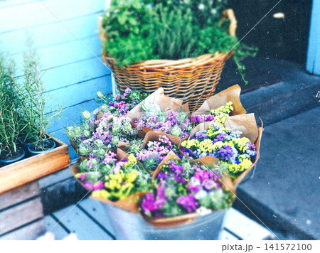 Fresh handmade flower bouquets displayed at a local flower shop with herbs and wicker baskets. Rustic floral market scene, cottage garden charm. 141572100