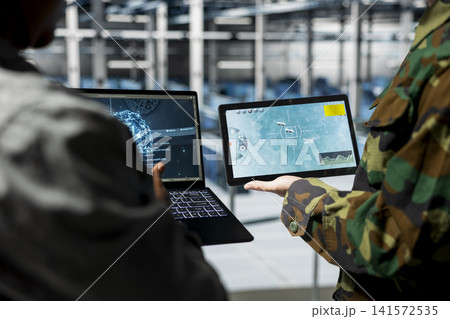 Close up of military server hub personnel analyzing AI machine learning powered surveillance data together. Data center army experts discussing artificial intelligence generated target coordinates Close up of military server hub personnel analyzing AI machine learning powered surveillance data together. Data center army experts discussing artificial intelligence generated target coordinates 141572535