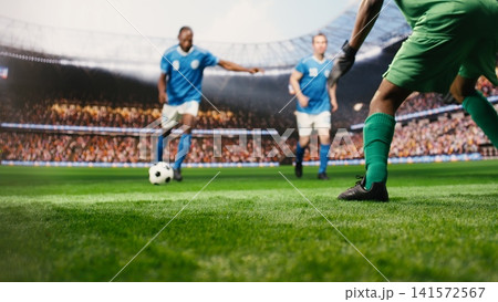 Selective focus of striker kicking ball in net for winning goal, shooting shot in front of goalkeeper during match action. Player in motion attacking net to score goal. Selective focus of striker kicking ball in net for winning goal, shooting shot in front of goalkeeper during match action. Player in motion attacking net to score goal. 141572567