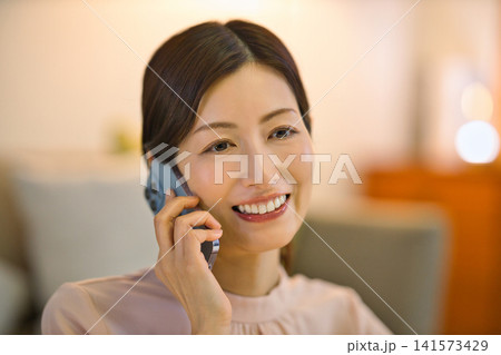 夜部屋でリラックスしてスマホを見る40代の女性 夜部屋でリラックスしてスマホを見る40代の女性 141573429