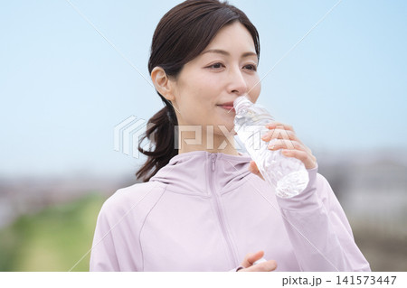 ウォーキング中にペットボトルの水を飲むミドル女性 141573447
