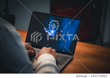 Person typing on laptop displaying a glowing blue hologram of a hand holding a shield with cryptocurrency symbol. Concept of blockchain security, safe digital investment and crypto wallet. 141573663