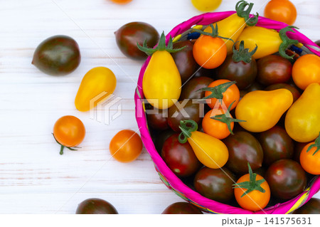 Colorful organic cherry tomatoes on the white wooden table. Colorful organic cherry tomatoes on the white wooden table. 141575631