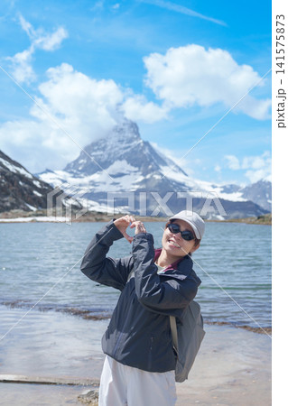Woman Tourist Exploring Zermatt, Switzerland. Traveler Making Heart Shape with Hands at Riffelsee Lake and Matterhorn, Famous European Landmark, Hiking Attraction, Travel Destination in Europe 141575873