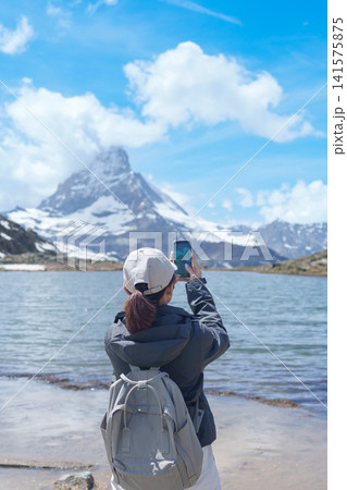 Woman Tourist Exploring Zermatt, Switzerland. Traveler Taking Photo with Smartphone at Riffelsee Lake and Iconic Matterhorn, Famous European Landmark, Hiking Attraction, Travel Destination in Europe Woman Tourist Exploring Zermatt, Switzerland. Traveler Taking Photo with Smartphone at Riffelsee Lake and Iconic Matterhorn, Famous European Landmark, Hiking Attraction, Travel Destination in Europe 141575875