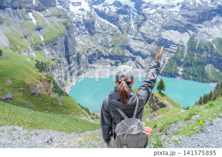 Woman Tourist Explore Oeschinensee, Kandersteg, Switzerland in Summer. Hiker Enjoy the Famous Turquoise Alpine Lake and Hiking Trail View, Popular Europe Tourist Attraction and Travel Destination Woman Tourist Explore Oeschinensee, Kandersteg, Switzerland in Summer. Hiker Enjoy the Famous Turquoise Alpine Lake and Hiking Trail View, Popular Europe Tourist Attraction and Travel Destination 141575895