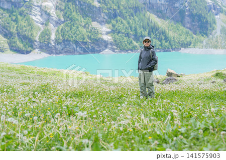 Woman Tourist Explore Oeschinensee, Kandersteg, Switzerland in Summer. Hiker Enjoy Hiking Trail, Wildflowers and Turquoise Alpine Lake, Popular European Tourist Attraction and Travel Destination Woman Tourist Explore Oeschinensee, Kandersteg, Switzerland in Summer. Hiker Enjoy Hiking Trail, Wildflowers and Turquoise Alpine Lake, Popular European Tourist Attraction and Travel Destination 141575903