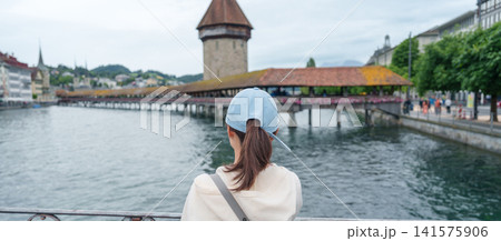 Woman Tourist Explore Lucerne, Switzerland in Summer. Traveler Visit Chapel Bridge and Water Tower on Reuss River. Famous European Landmark, Popular Tourist Attraction and Travel Destination in Europe Woman Tourist Explore Lucerne, Switzerland in Summer. Traveler Visit Chapel Bridge and Water Tower on Reuss River. Famous European Landmark, Popular Tourist Attraction and Travel Destination in Europe 141575906