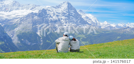 Couple Tourist Exploring Grindelwald First, Switzerland in Summer. happy Hiker sightseeing Swiss Alps in Jungfrau Region. Famous Traveler Attraction, Travel Destination and hiking trail in Europe Couple Tourist Exploring Grindelwald First, Switzerland in Summer. happy Hiker sightseeing Swiss Alps in Jungfrau Region. Famous Traveler Attraction, Travel Destination and hiking trail in Europe 141576017