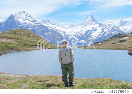 man Tourist Explore Grindelwald First, Switzerland in Summer. Hiker visit Bachalpsee Lake and Swiss Alps in Jungfrau Region. Famous Traveler Attraction, Travel Destination and hiking trail in Europe 141576049