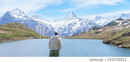 man Tourist Explore Grindelwald First, Switzerland in Summer. Hiker visit Bachalpsee Lake and Swiss Alps in Jungfrau Region. Famous Traveler Attraction, Travel Destination and hiking trail in Europe 141576051