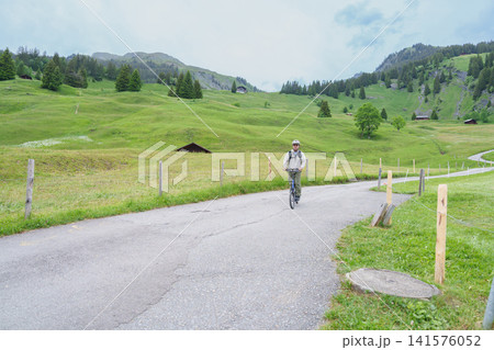 man Tourist Riding First Trottibike from Bort to Grindelwald, Switzerland in Summer. Scenic Alpine Meadows, Farmhouses, Adventure Activity, Famous Travel Destination in Europe. Top of Adventure 141576052