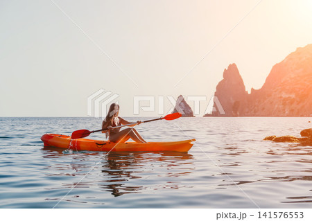 Kayaking Woman Sea Scenic Landscape - A woman kayaks in a scenic landscape with a rocky mountain in the background. 141576553