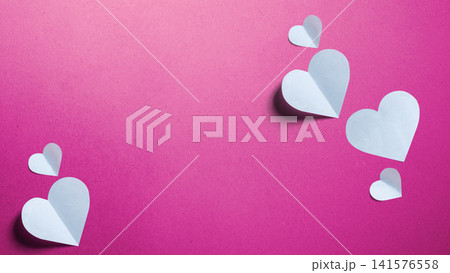 Minimalist concept of love and relationship featuring black paper cutouts of a man and a woman with a white folded paper heart on a textured pink background. Concept of First Love Day Minimalist concept of love and relationship featuring black paper cutouts of a man and a woman with a white folded paper heart on a textured pink background. Concept of First Love Day 141576558