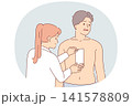 Depilation hair on chest of man, experiencing pain from tearing wax tape, stands near cosmetologist 141578809
