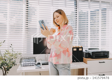 Happy beautiful Hispanic businesswoman using web service on smartphone in office workspace, working on online project on mobile phone, typing on cellphone, smiling. Banner shot Happy beautiful Hispanic businesswoman using web service on smartphone in office workspace, working on online project on mobile phone, typing on cellphone, smiling. Banner shot 141579478