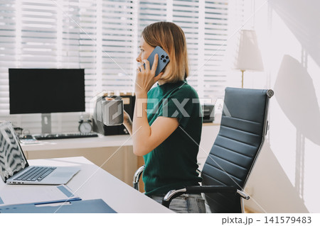 Happy female entrepreneur using smart phone in office. 141579483