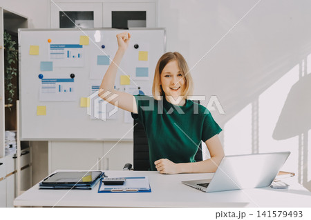 Concept of business working, Businesswoman sitting while writing and checking business analytic document report and holding tablet with computer pc, smartphone on desk in her workstation. Concept of business working, Businesswoman sitting while writing and checking business analytic document report and holding tablet with computer pc, smartphone on desk in her workstation. 141579493