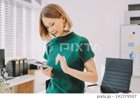 Closeup image of a businesswoman using mobile phone in office Closeup image of a businesswoman using mobile phone in office 141579507