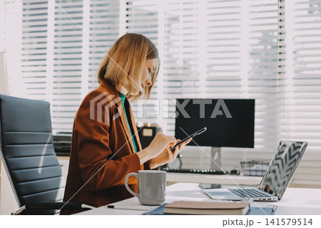 Woman smiling to herself as she works in an office 141579514