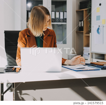 Woman smiling to herself as she works in an office Woman smiling to herself as she works in an office 141579515