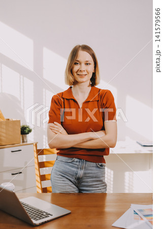 Young woman works on a touchpad, feeling comfortable at cozy home office with a green plant on the background Young woman works on a touchpad, feeling comfortable at cozy home office with a green plant on the background 141579566
