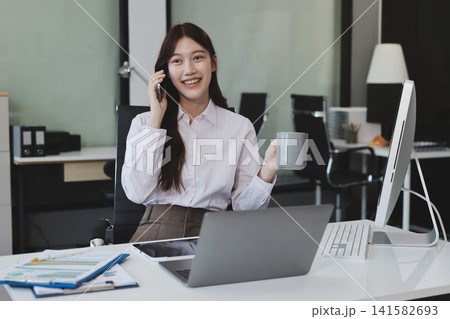 Young businesswoman professional employee using pc doing online banking analysing at workplace. Asian middle-aged business woman working on laptop computer in office, taking notes. Banner, copy space Young businesswoman professional employee using pc doing online banking analysing at workplace. Asian middle-aged business woman working on laptop computer in office, taking notes. Banner, copy space 141582693