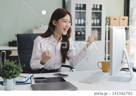 Young businesswoman professional employee using pc doing online banking analysing at workplace. Asian middle-aged business woman working on laptop computer in office, taking notes. Banner, copy space Young businesswoman professional employee using pc doing online banking analysing at workplace. Asian middle-aged business woman working on laptop computer in office, taking notes. Banner, copy space 141582702