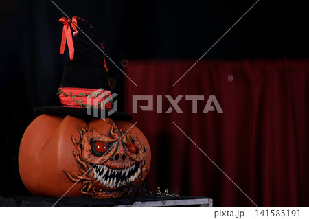 Spooky Halloween pumpkin with witch hat and menacing grin at dusk Spooky Halloween pumpkin with witch hat and menacing grin at dusk 141583191
