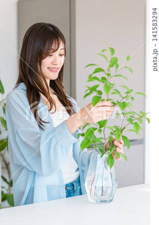 フラワーベース,花瓶に植物を入れる若い女性 141583294