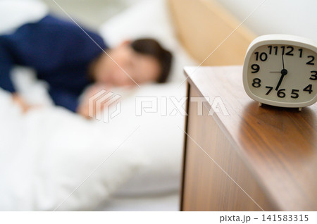 ベッドで眠る日本人女性と目覚まし時計 ベッドで眠る日本人女性と目覚まし時計 141583315