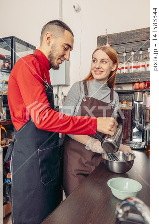 two baristas preparing ingredients and mixing in bowl behind cafe counter teamwork in coffee shop kitchen small business workflow concept of collaboration and food preparation two baristas preparing ingredients and mixing in bowl behind cafe counter teamwork in coffee shop kitchen small business workflow concept of collaboration and food preparation 141583344