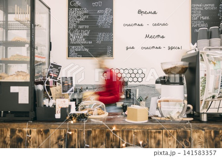 A busy cafe scene with a barista preparing coffee. . The cafe has a warm, inviting atmosphere. Busy barista, blurred in motion A busy cafe scene with a barista preparing coffee. . The cafe has a warm, inviting atmosphere. Busy barista, blurred in motion 141583357
