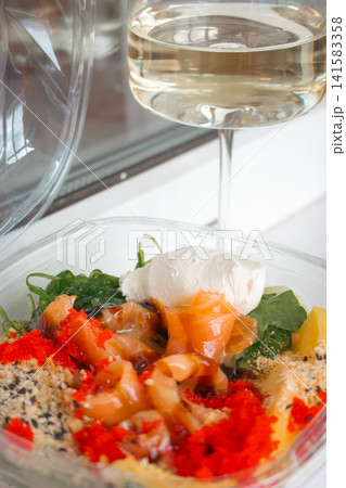 Seafood bowl with rice and vegetables and glass of white wine. Wineglass and fish poke. Fresh food to go. Salmon with salad close up. Seafood restaurant menu. Seafood box with cream cheese. Seafood bowl with rice and vegetables and glass of white wine. Wineglass and fish poke. Fresh food to go. Salmon with salad close up. Seafood restaurant menu. Seafood box with cream cheese. 141583358