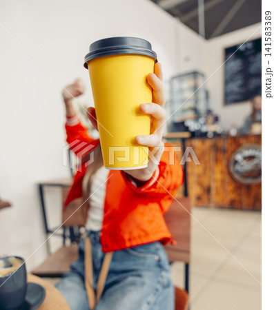 woman holding yellow takeaway coffee cup toward camera in cafe selective focus close up of hand with disposable cup modern lifestyle concept of coffee to go and urban daily routine woman holding yellow takeaway coffee cup toward camera in cafe selective focus close up of hand with disposable cup modern lifestyle concept of coffee to go and urban daily routine 141583389