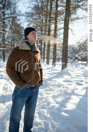 Man standing in snowy forest enjoying winter sunlight Man standing in snowy forest enjoying winter sunlight 141583459