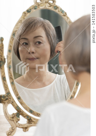 鏡の前でヘアセットをするシニア女性 鏡の前でヘアセットをするシニア女性 141583503